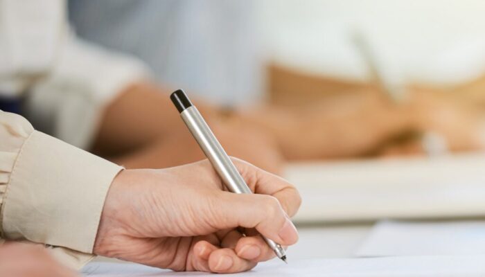 Hand of business lady signing agreement at meeting